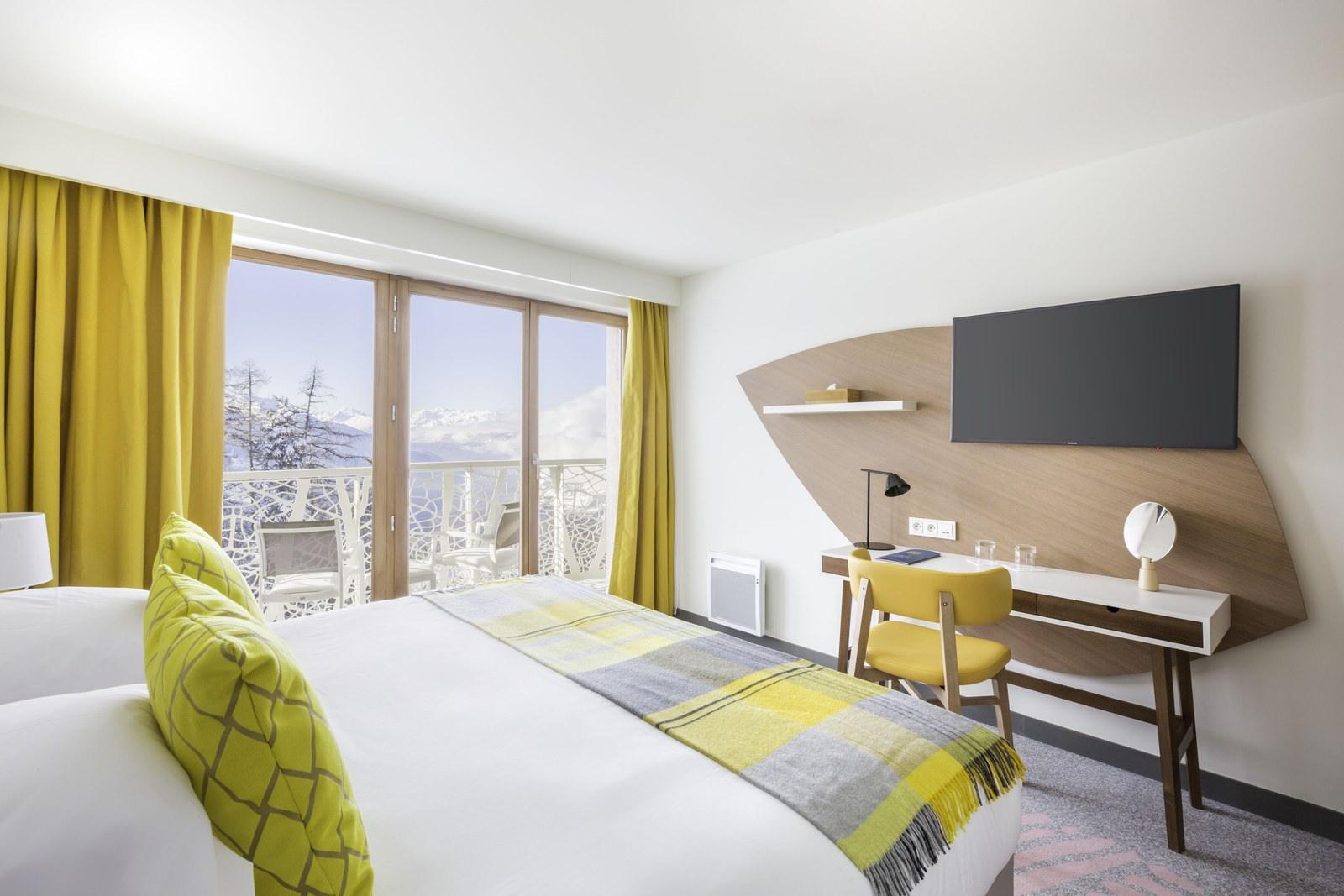 Bedroom with yellow accents and a snowy balcony view at Club Med Les Arcs Panorama