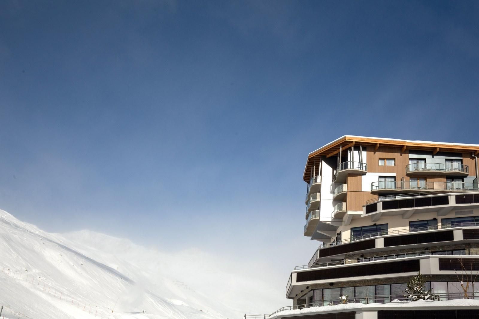 Club Med Tignes beside a snowy ski slope under a blue sky