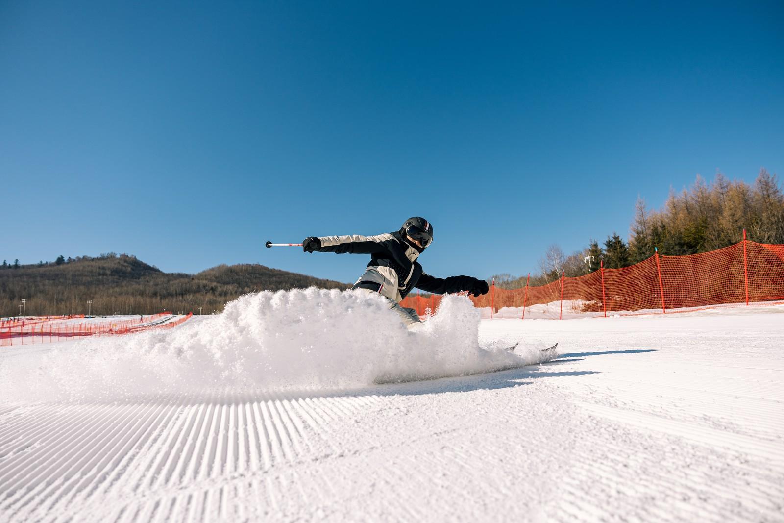 Skier carving on a snowy slope at Club Med Changbaishan