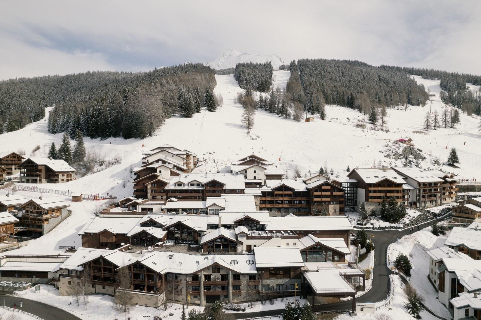 Snow-covered chalet-style buildings at Club Med Peisey-Vallandry below forested ski slopes