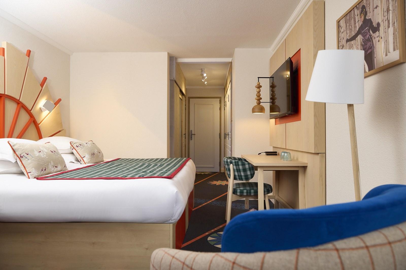 Bedroom with a sundial-shaped headboard and green plaid bed runner at Club Med Serre Chevalier
