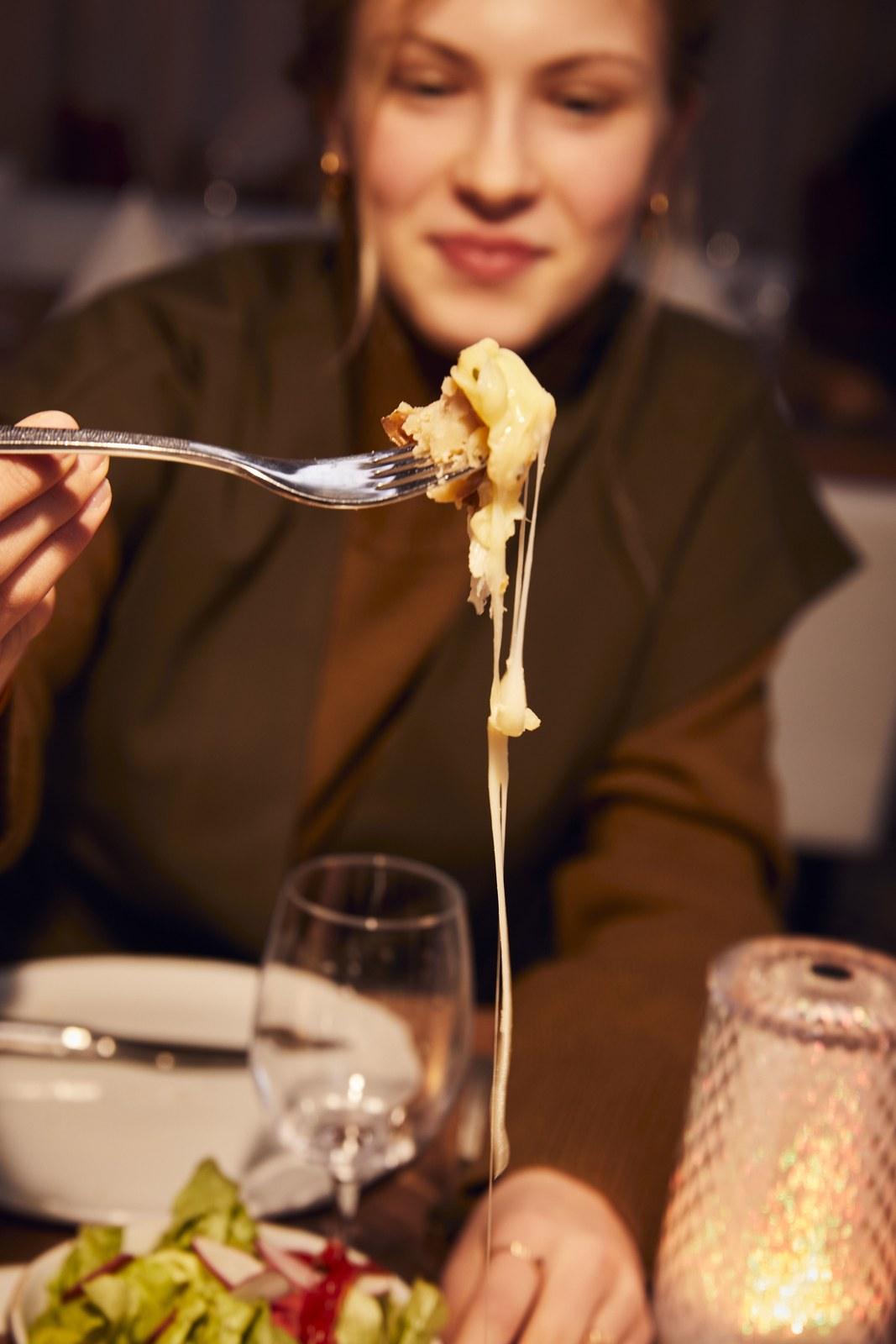 Guest lifting melted cheese with a fork at Club Med Grand Massif Samoëns Morillon