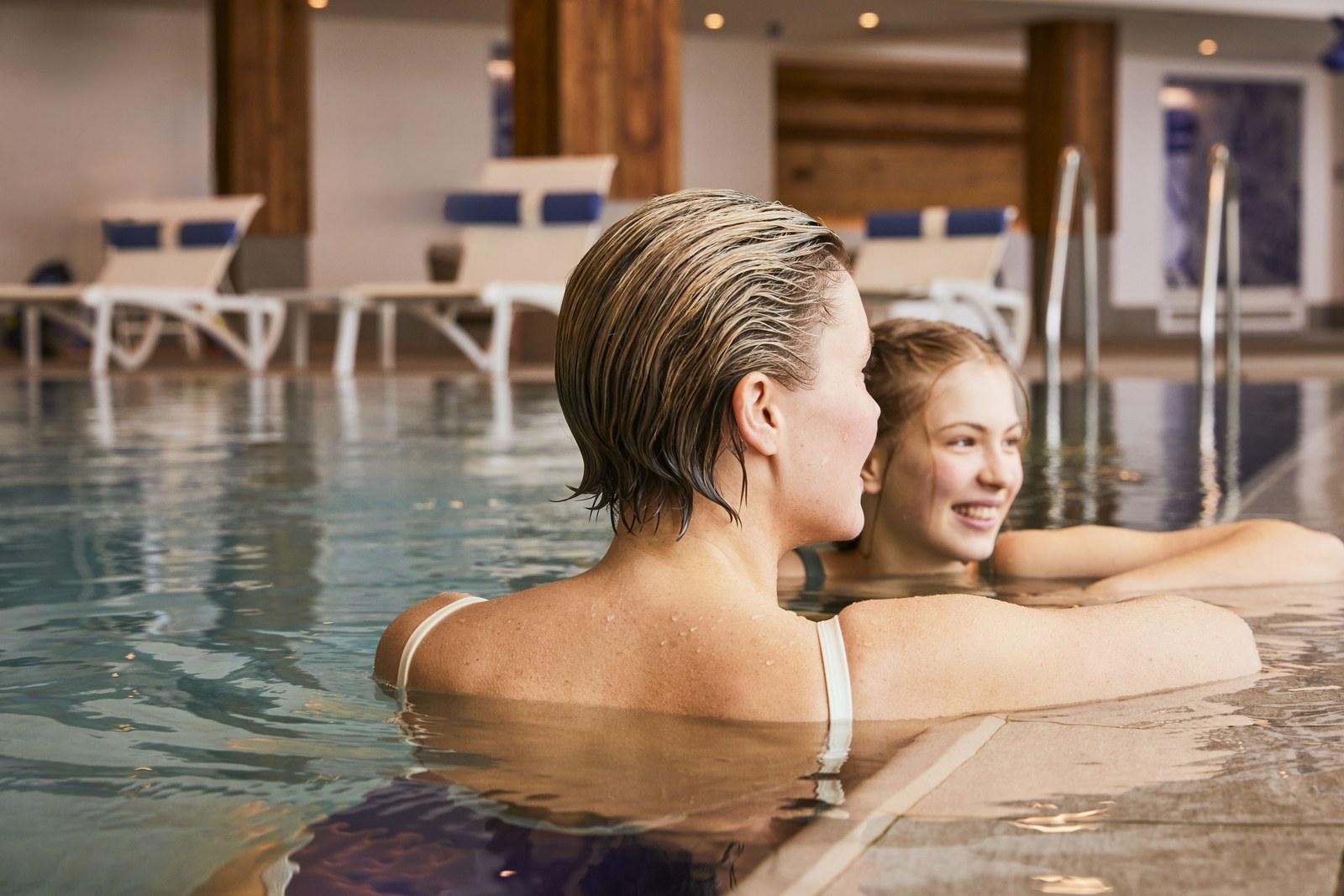 Two guests smiling at the edge of the indoor pool at Club Med Grand Massif Samoëns Morillon