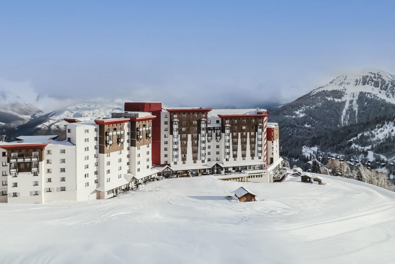 Club Med La Plagne 2100 surrounded by snow beneath a blue sky