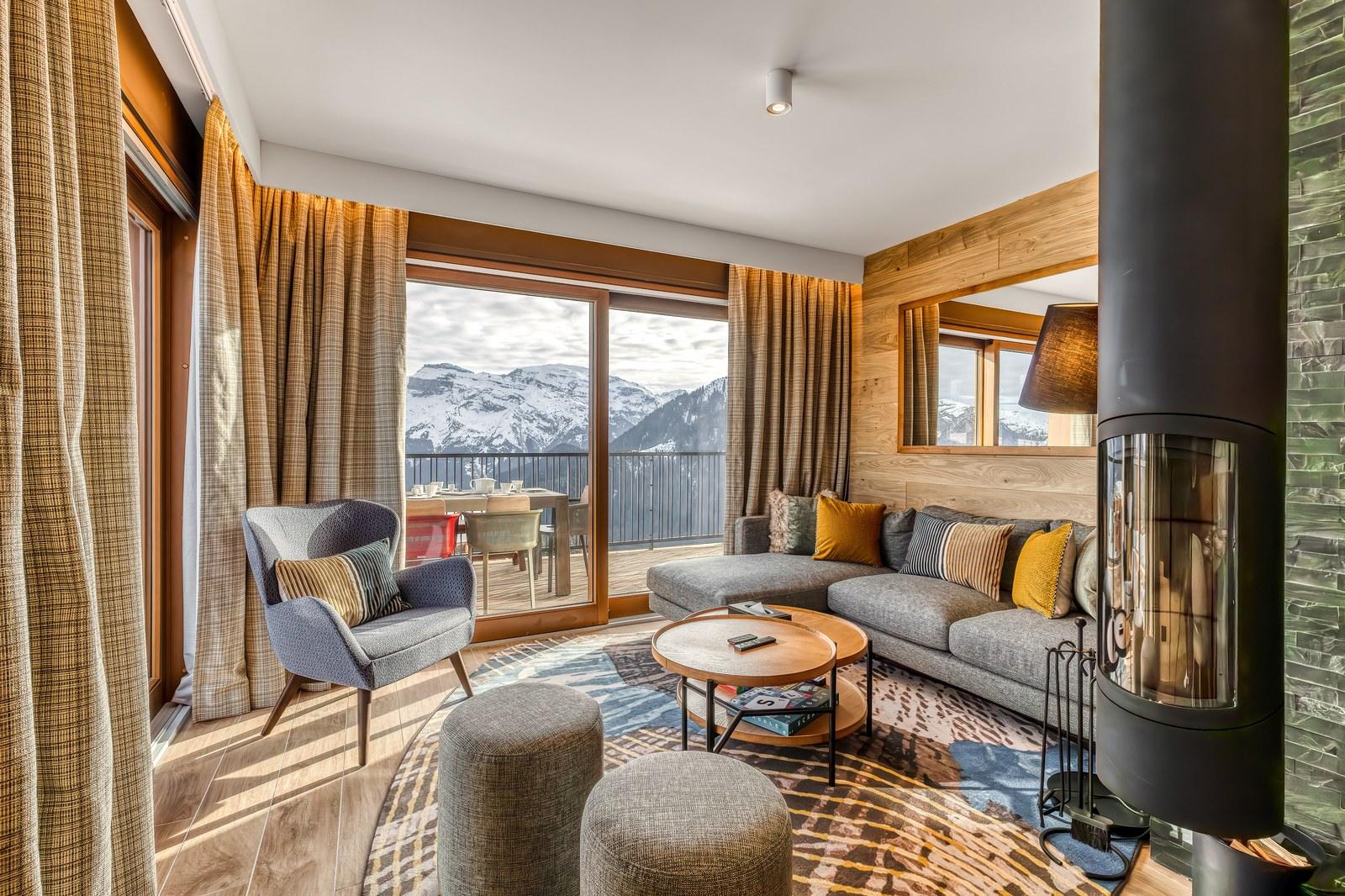 Private chalet lounge with a fireplace and snowy mountain views at Grand Massif Chalet-Apartments